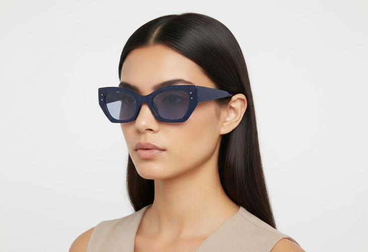 Woman wearing blue sunglasses against a light gray background