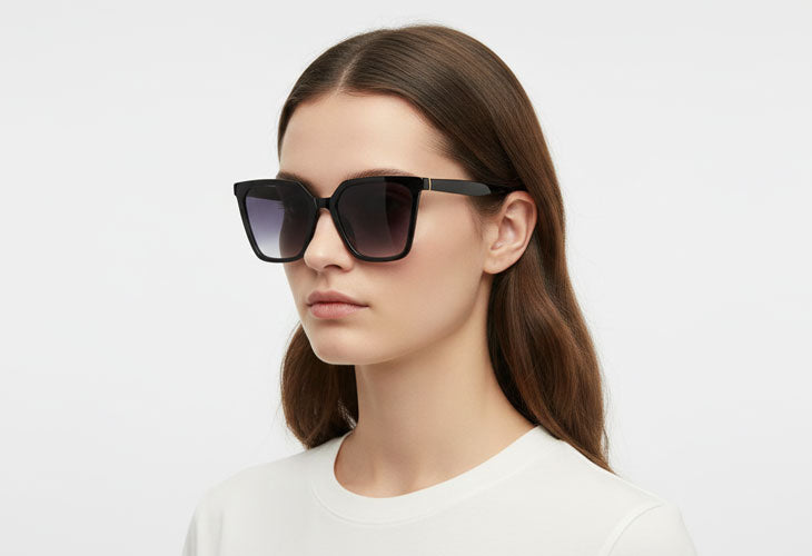 Woman wearing dark sunglasses on a light gray background