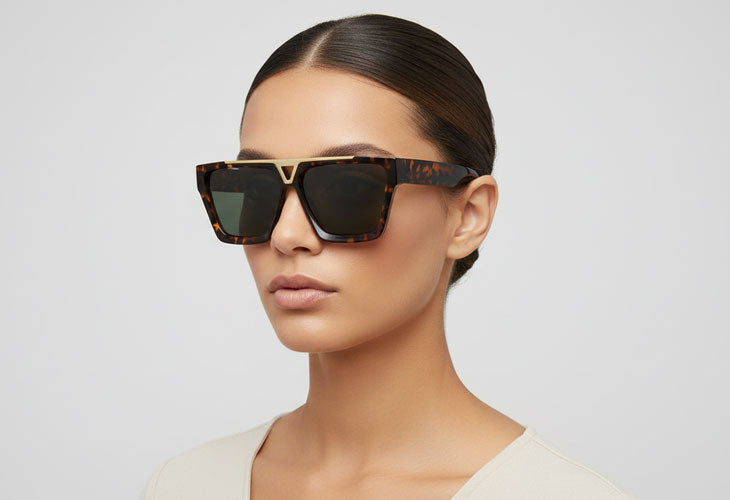 Woman wearing a pair of sunglasses with a neutral background