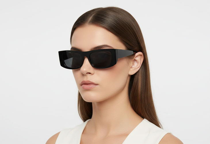 Woman wearing black sunglasses against a white background