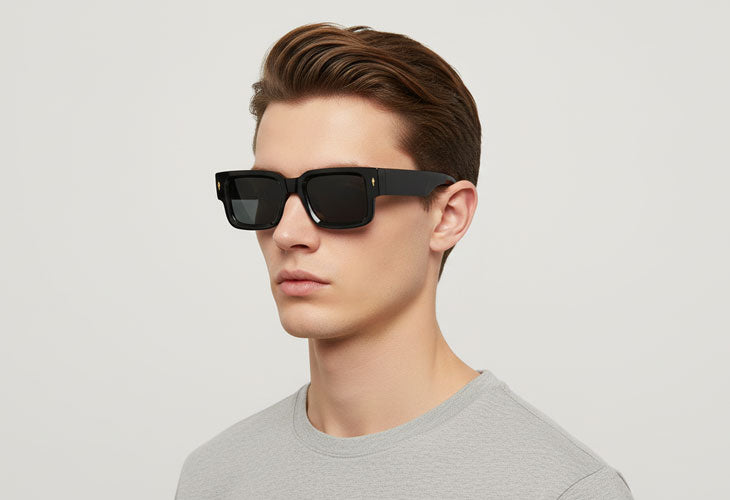 Man wearing black sunglasses and a gray shirt on a light gray background