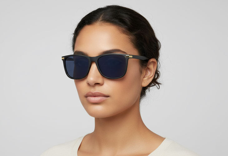 Woman wearing dark sunglasses against a plain background