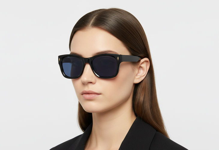 Woman wearing dark sunglasses against a light gray background