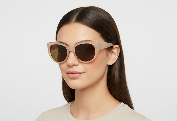 Woman wearing cat-eye sunglasses with a plain background