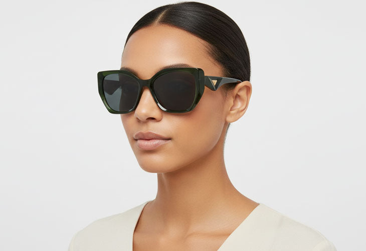 Woman wearing dark sunglasses against a plain background