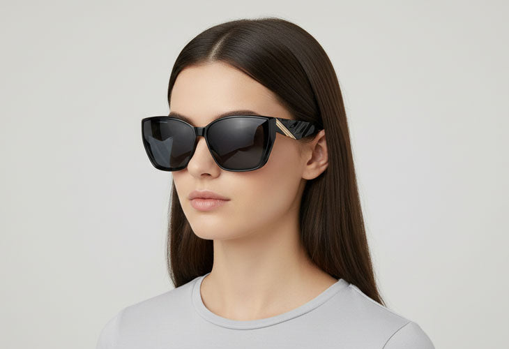 Woman wearing black sunglasses against a plain background