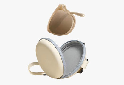 beige Wholesale Oval Folding Sunglasses folded in half in front of a open carrying case