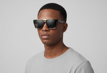 Man wearing sunglasses and a gray shirt against a plain background